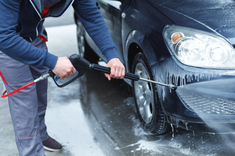 Person som sköljer av en bil med lufttryckstvätt.