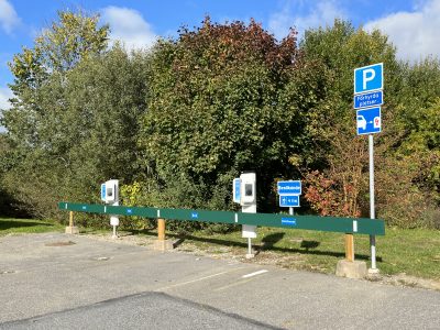 Fyra parkeringsplatser med laddboxar. Träd i bakgrunden.