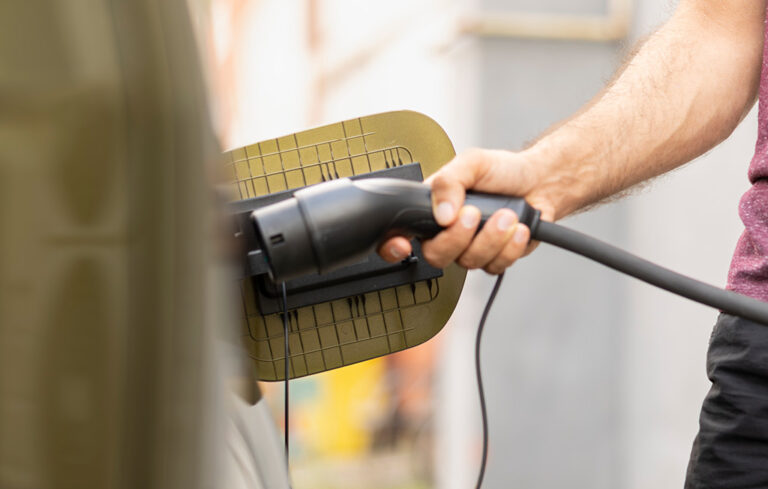 Person som stoppar in en laddare i sin elbil.