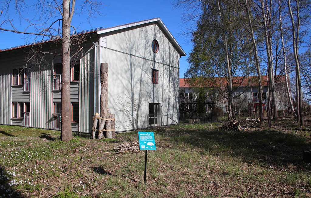 Skogsområde med en skylt som informerar om nyttan med faunadepåer.