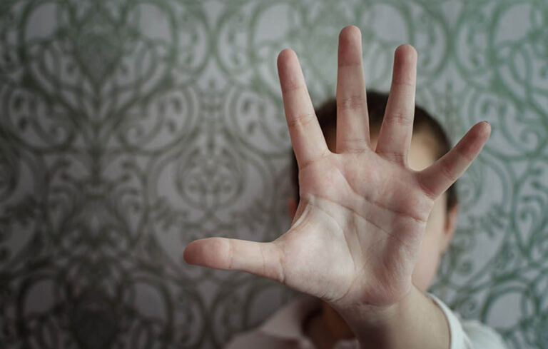 En person som sträcker ut sin hand framför sitt ansikte.