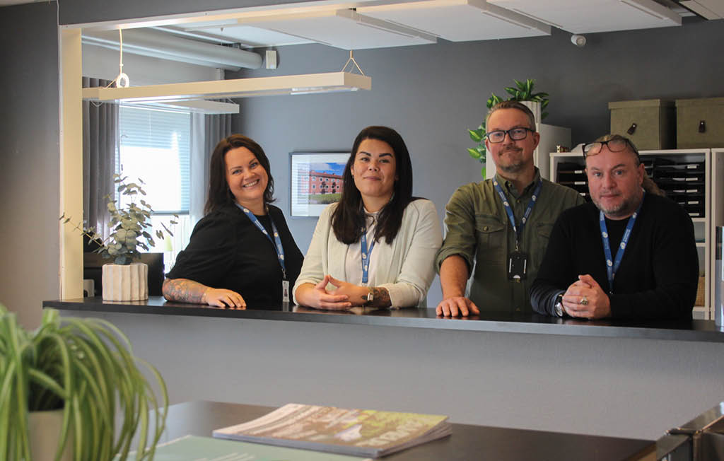 Fyra medarbetare står lutade över en receptionsdisk.